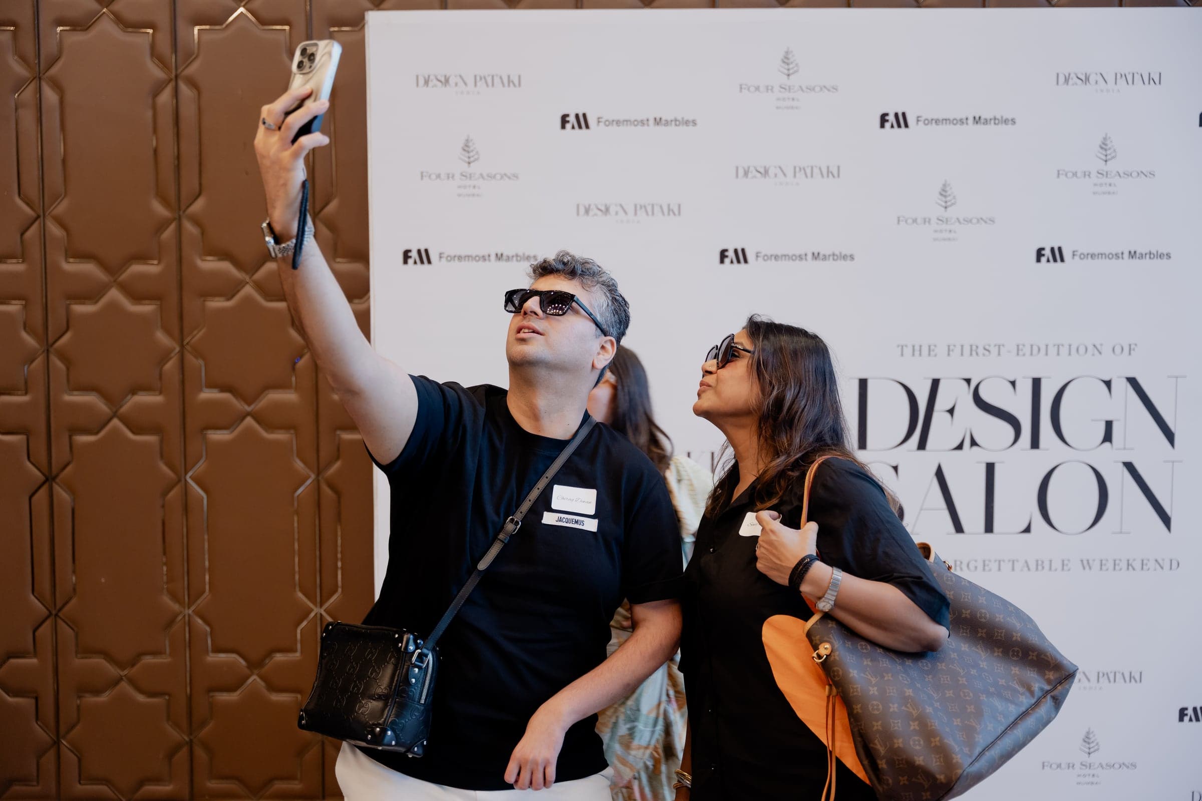 Guests taking a photo at an event step-and-repeat backdrop